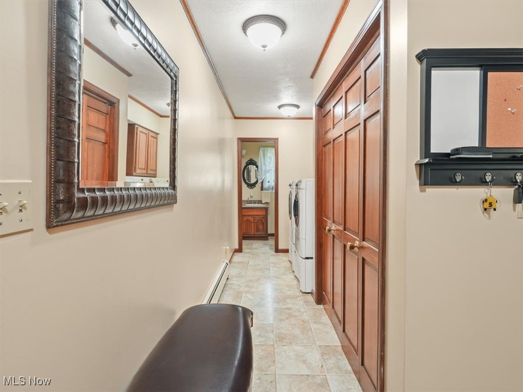 Hallway with a ornamental molding, a textured ceiling, and washer / dryer