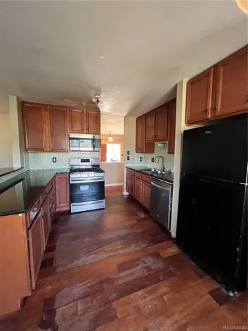 a kitchen with stainless steel appliances granite countertop a refrigerator stove top oven a sink and dishwasher with wooden floor