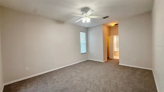 an empty room with chandelier fan and windows