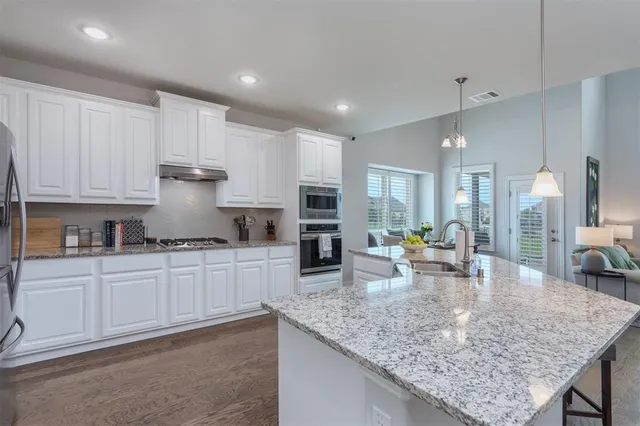a kitchen with stainless steel appliances kitchen island granite countertop a refrigerator and a stove top oven