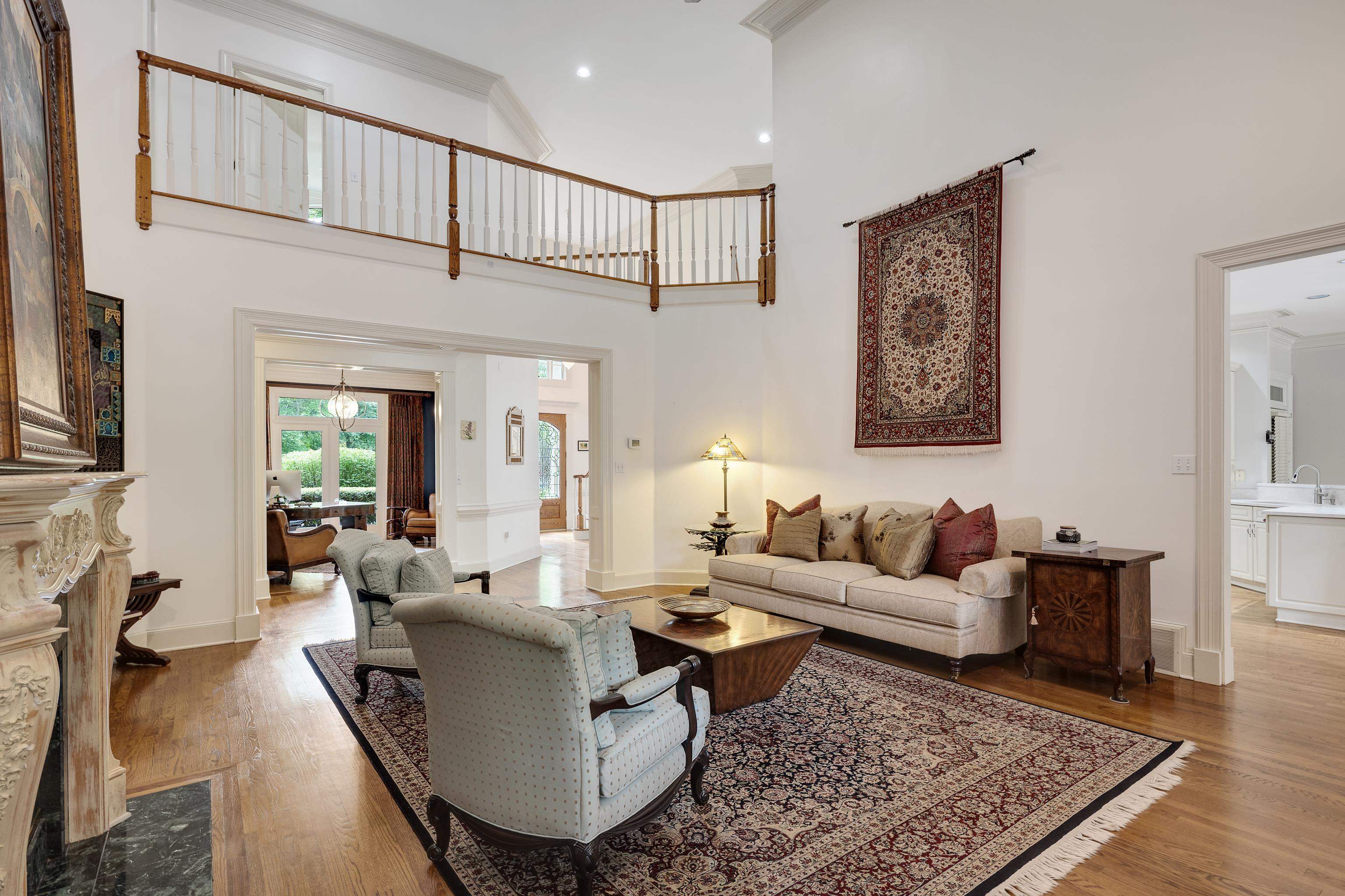 350 Bluff Ridge Cove Memphis, TN 38018 - Photo 15 of 37 Two-story living area with hardwood flooring, a decorative fireplace with carved mantel, and an upper-level balcony featuring wood railings