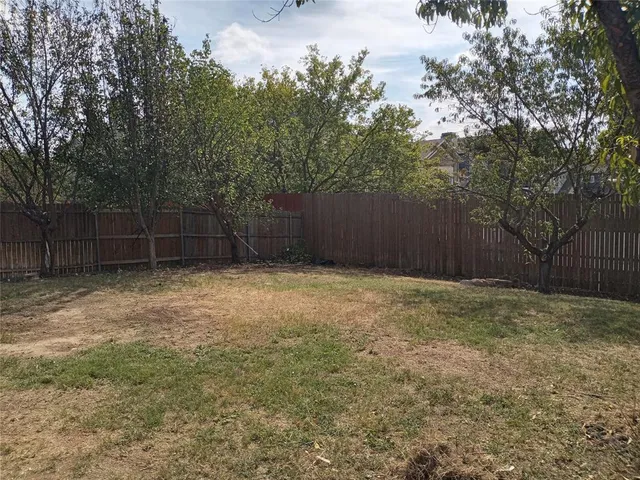 a view of a backyard with trees and wooden fence