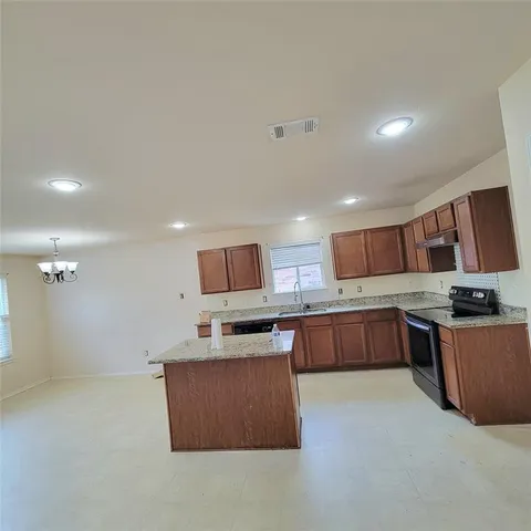a kitchen with stainless steel appliances granite countertop a stove top oven a sink a counter space and cabinets