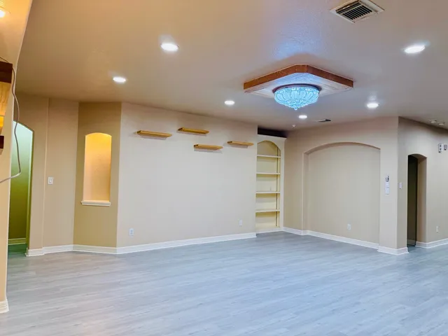 an empty room with wooden floor and a ceiling fan