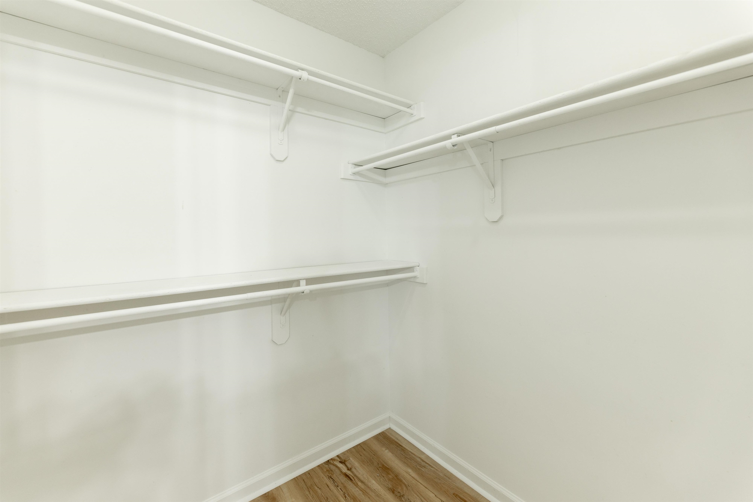 7421 Richmond Road Memphis, TN 38125 - Photo 26 of 39 Walk-in closet featuring white walls, wood-finish flooring, white baseboards, and built-in white wire shelving and hanging rods