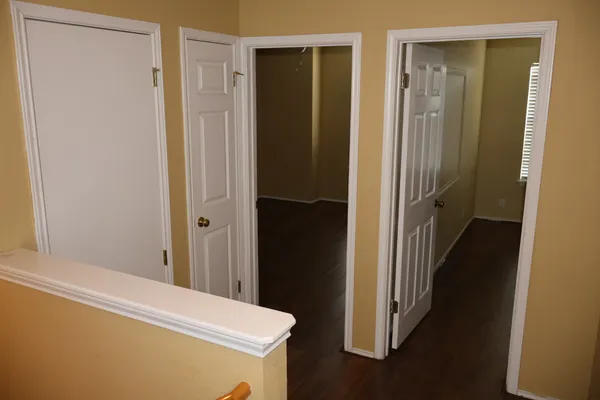 an empty room with wooden floor closet and windows
