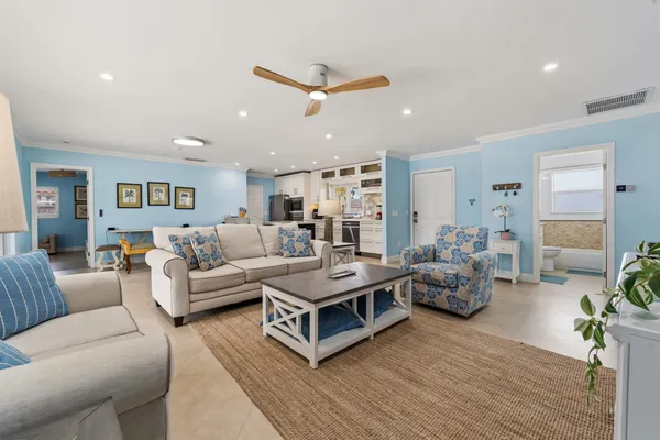 a living room with furniture kitchen view and a wooden floor