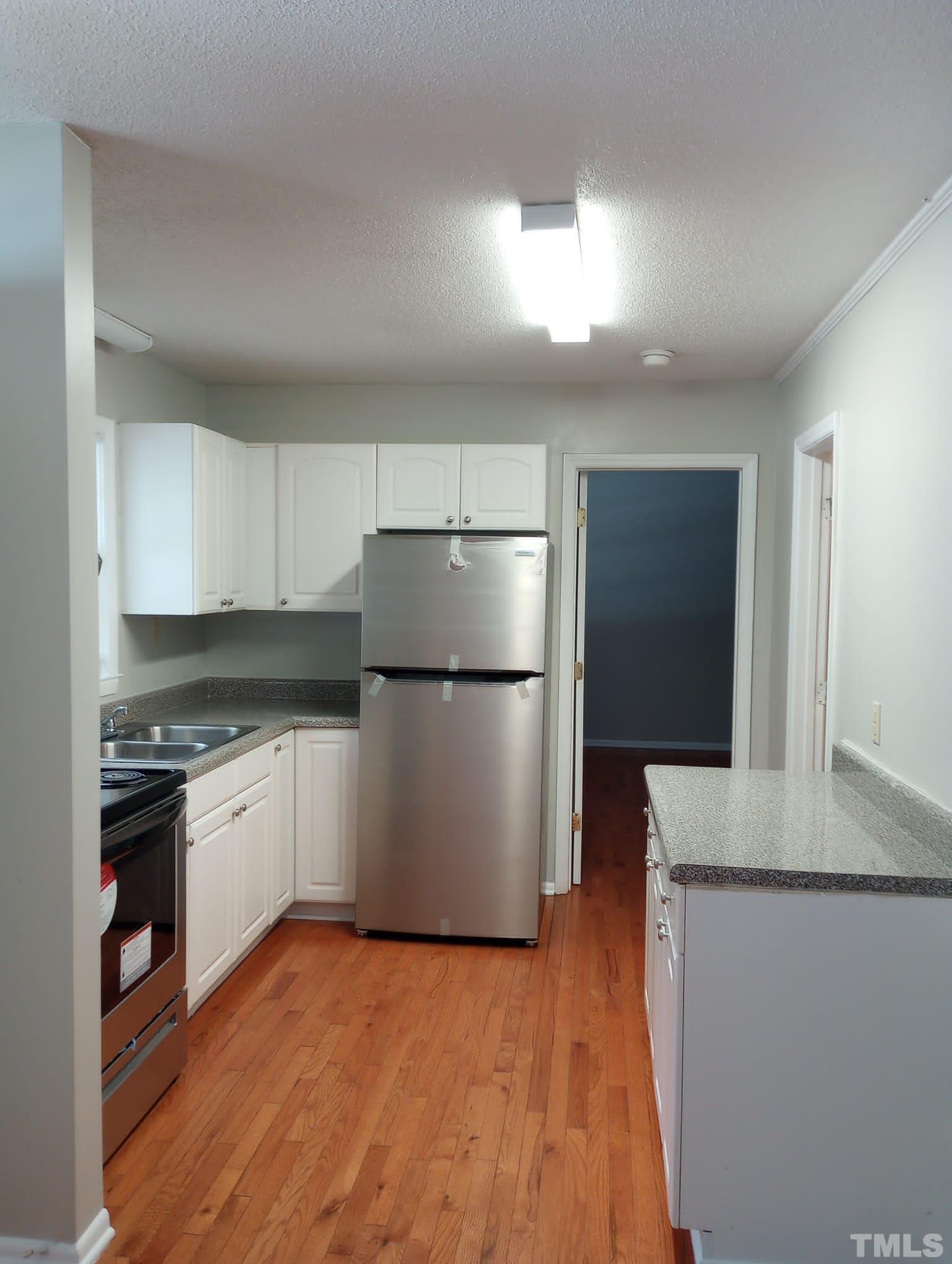 1011 Morreene Road, Unit 31 Durham, NC 27705 - Photo 2 of 5 a kitchen with granite countertop a refrigerator and a stove top oven