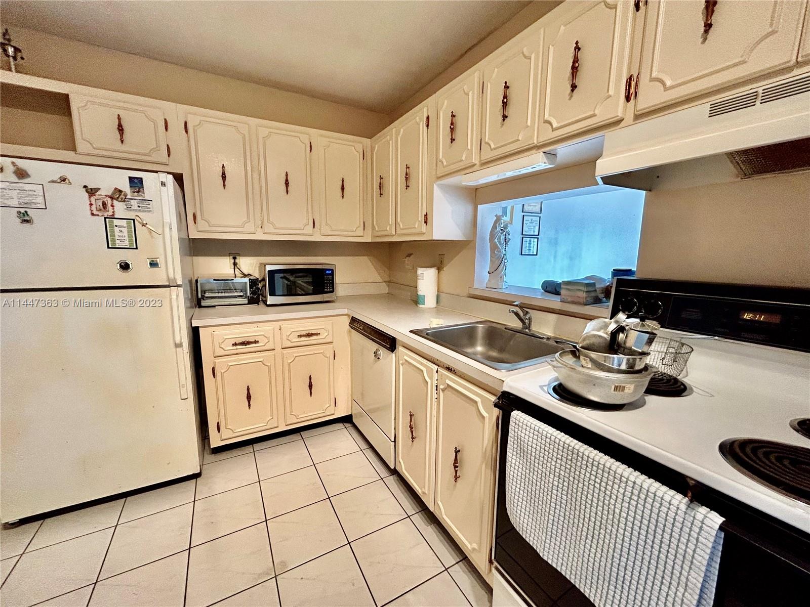 5201 Northwest 7th Street, Unit 403 Miami, FL 33126 - Photo 10 of 17 a kitchen with white cabinets a sink and white appliances