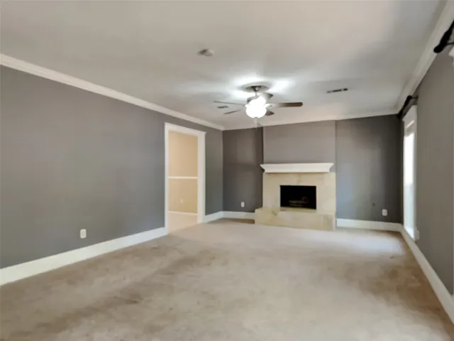 an empty room with a fireplace and chandelier fan
