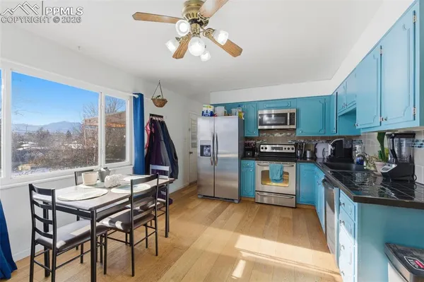 a kitchen with stainless steel appliances granite countertop a stove top oven a sink a dining table and chairs