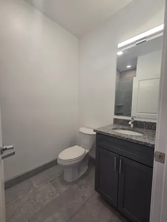 a bathroom with a granite countertop toilet a sink and a mirror
