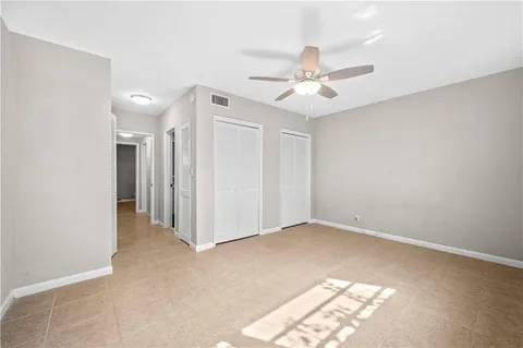 an empty room with windows and fan