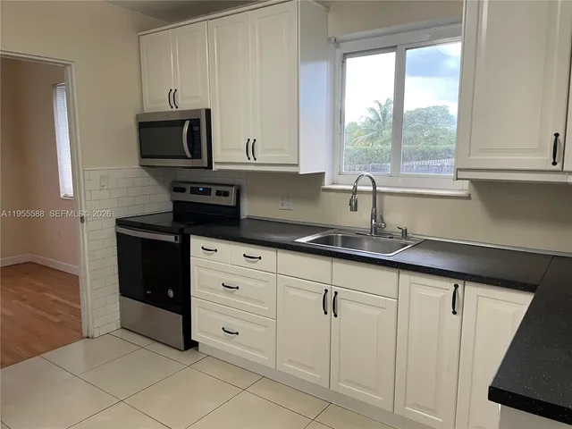 a kitchen with white cabinets and a window