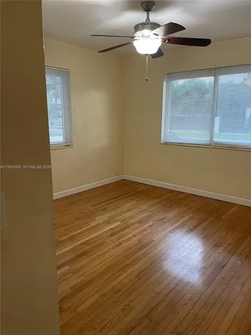 a view of empty room with wooden floor and fan