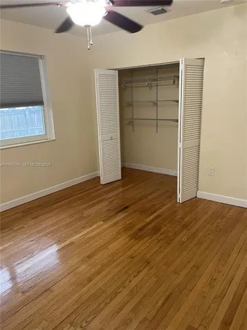 an empty room with wooden floor closet and windows