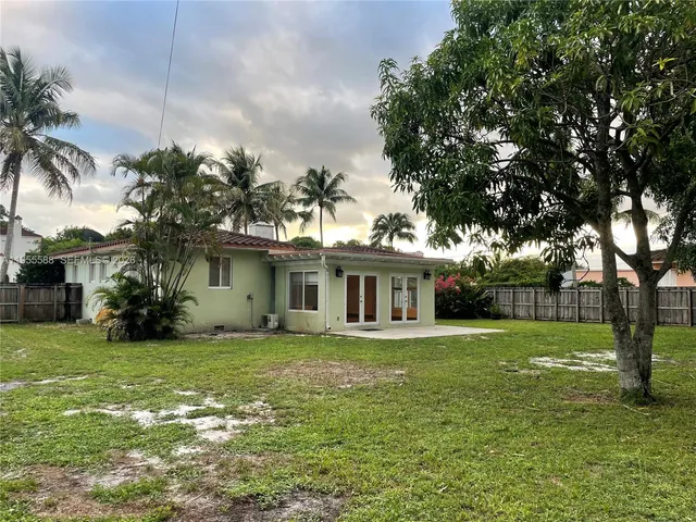 a front view of a house with a garden and trees