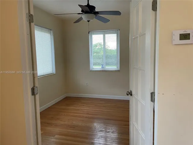 a view of an empty room with wooden floor and a window