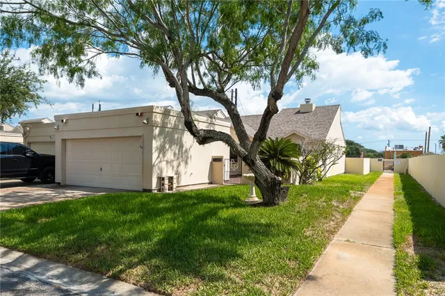 a view of a house with a yard and a large tree