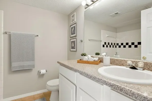 a bathroom with a granite countertop sink mirror vanity and toilet
