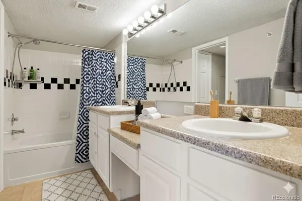 a bathroom with a granite countertop sink a mirror a vanity and a shower