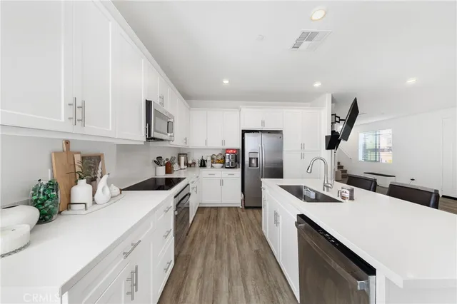 a kitchen with stainless steel appliances a sink a stove a refrigerator cabinets and a counter top space