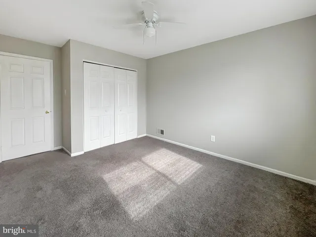 a view of an empty room and chandelier fan