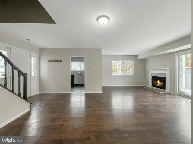 a view of an empty room with window and wooden floor