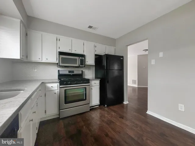a kitchen with a refrigerator stove and wooden cabinets