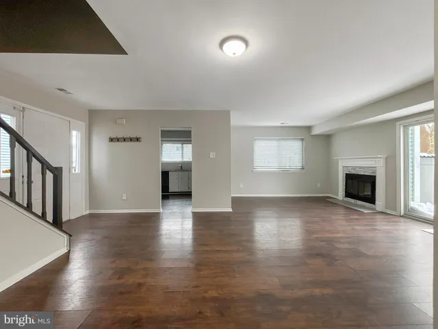 a view of an empty room with wooden floor fireplace and a window