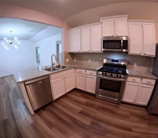 a kitchen with granite countertop a sink cabinets and stainless steel appliances