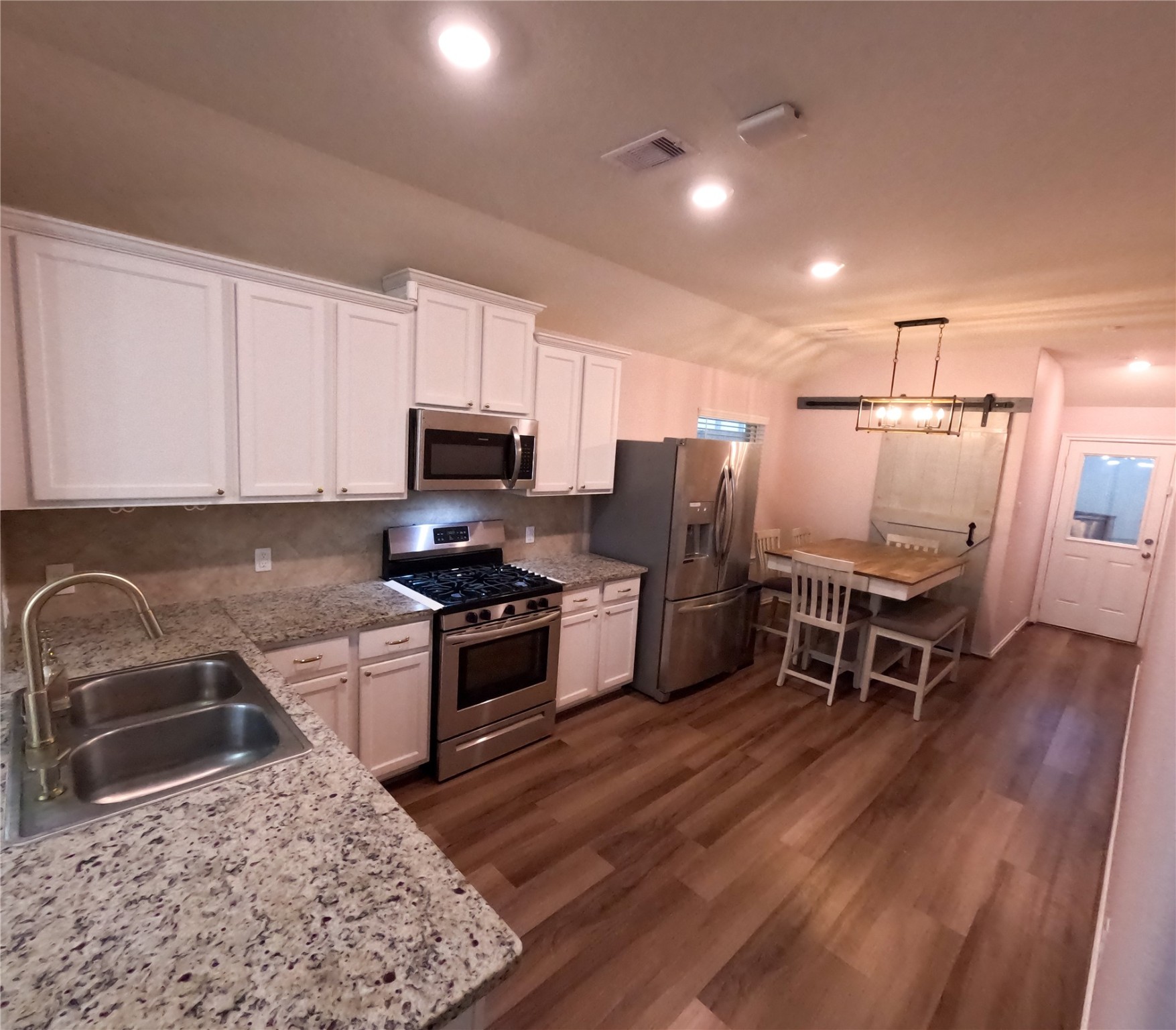 5515 Savanna Pasture Road Katy, TX 77493 - Photo 6 of 17 a kitchen with stainless steel appliances granite countertop a stove top oven a sink dishwasher a dining table and chairs with wooden floor