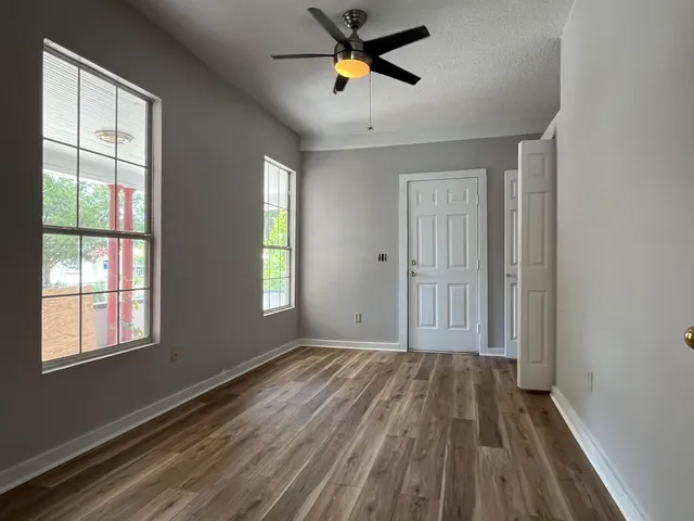 a view of empty room with wooden floor and fan
