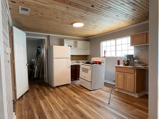 a kitchen with a refrigerator a stove top oven a sink and dishwasher with wooden floor