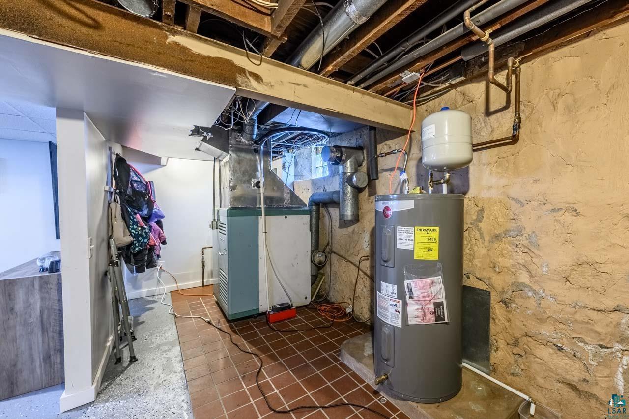 2581 O'Rourke Road Hibbing, MN 55746 - Photo 31 of 61 Basement utility area featuring a hot water heater, a furnace, and exposed ceiling joists