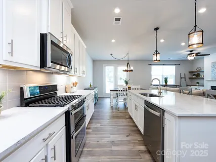 a kitchen with stainless steel appliances kitchen island granite countertop a sink a stove and a wooden floors