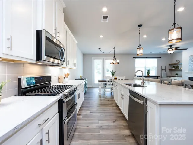 a kitchen with stainless steel appliances kitchen island granite countertop a sink a stove and a wooden floors
