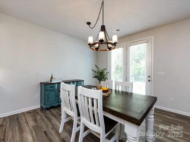 a view of a dining room and livingroom with furniture wooden floor kitchen view and a chandelier