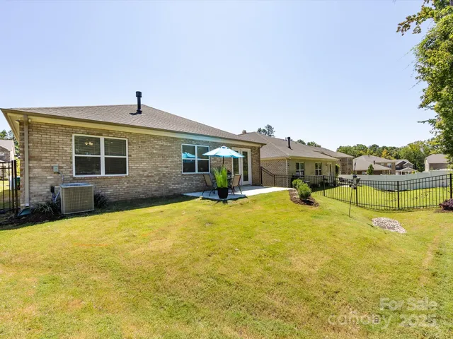 a view of a patio with table and chairs under an umbrella with large trees