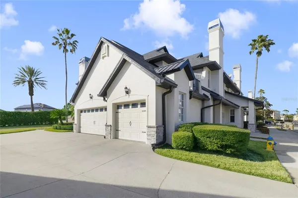 a view of a white house with large windows and a small yard