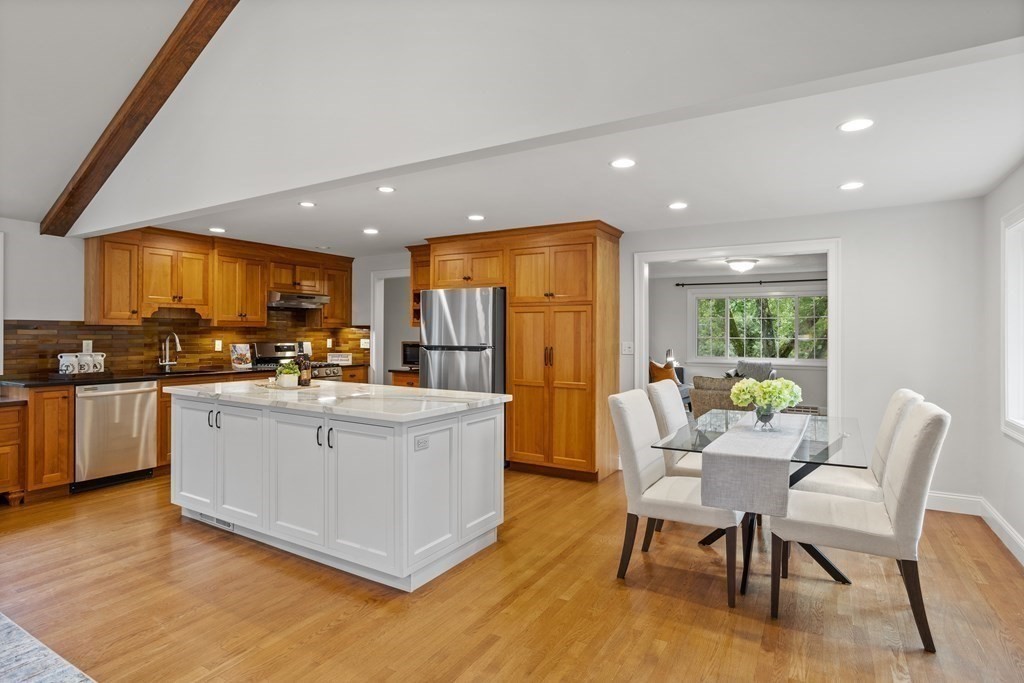 26 Alta Road Sudbury, MA 01776 - Photo 7 of 37 a kitchen with stainless steel appliances kitchen island granite countertop a stove a refrigerator a microwave a dining table and chairs with wooden floor
