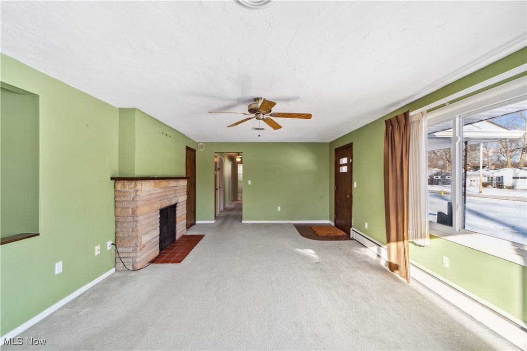 230 Fairfield Road Avon Lake, OH 44012 - Photo 5 of 40 Unfurnished living room featuring a fireplace, a baseboard heating unit, ceiling fan, and a healthy amount of sunlight