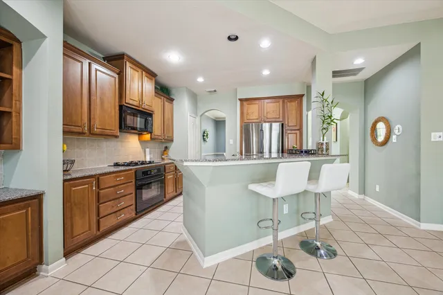 a large kitchen with stainless steel appliances granite countertop a stove a sink a dining table and chair