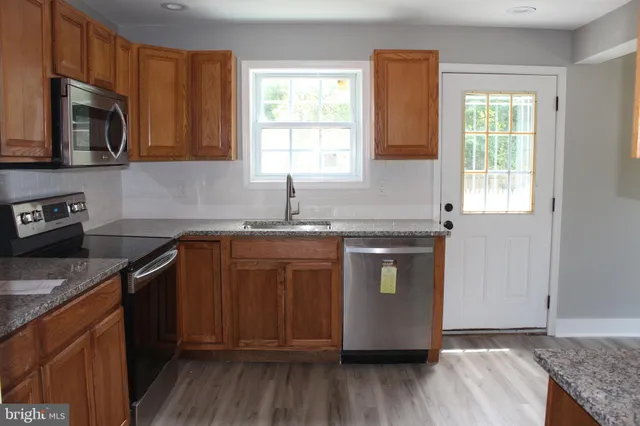 a kitchen with granite countertop wooden cabinets stainless steel appliances a window and a sink