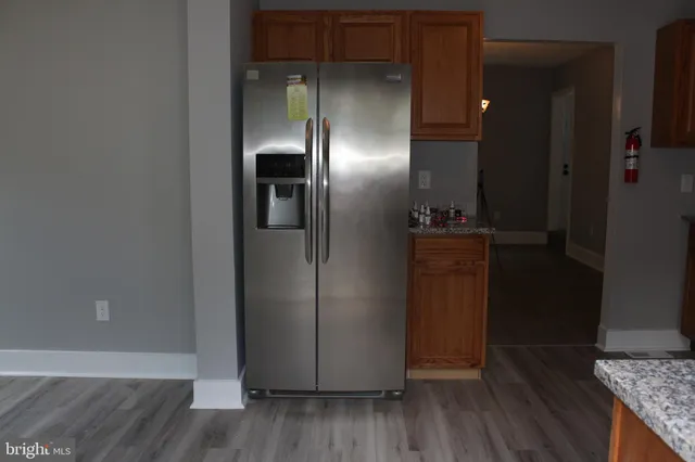an empty room with wooden floor and a kitchen