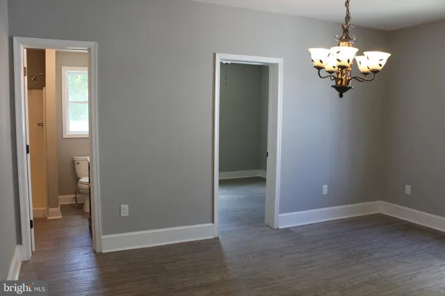 a view of a hallway with wooden floor and a chandelier