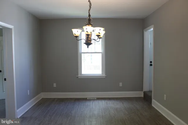 a view of a room with wooden floor chandelier and a window