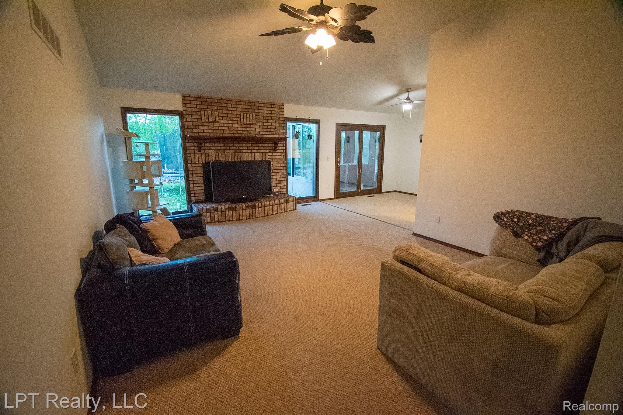 217 Nawakwa Road Rochester, MI 48307 - Photo 4 of 29 Carpeted living area with lofted ceiling, a fireplace, and ceiling fan