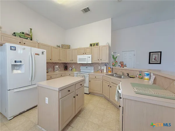 a kitchen with a sink a stove a refrigerator and white cabinets