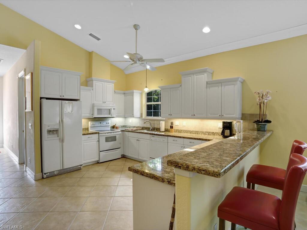 1079 Michigan Avenue Naples, FL 34103 - Photo 18 of 31 a kitchen with a refrigerator a sink and chairs